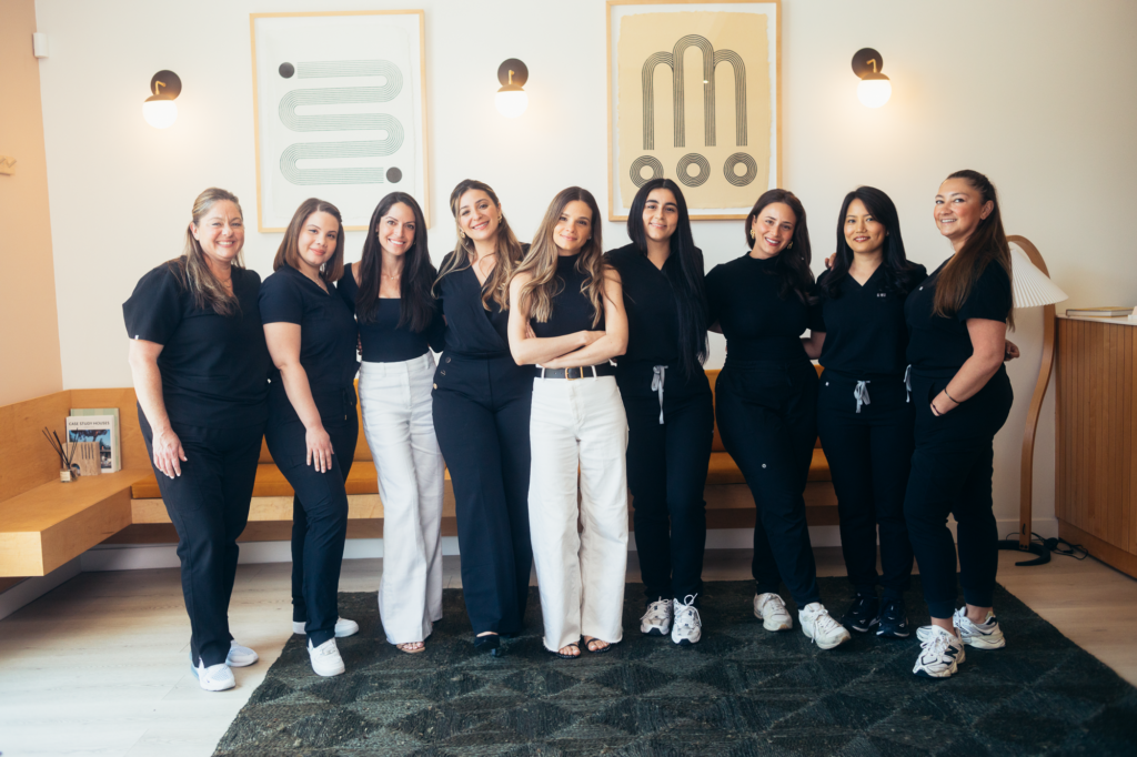 Professional dental team wearing black uniforms inside a contemporary dental office, showcasing a collaborative and welcoming environment.