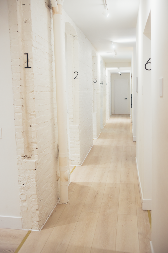 Bright hallway inside a modern dental clinic with numbered treatment rooms and minimalist interior design