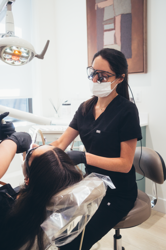 Dentist performing a dental procedure using professional equipment in a clean, modern treatment room