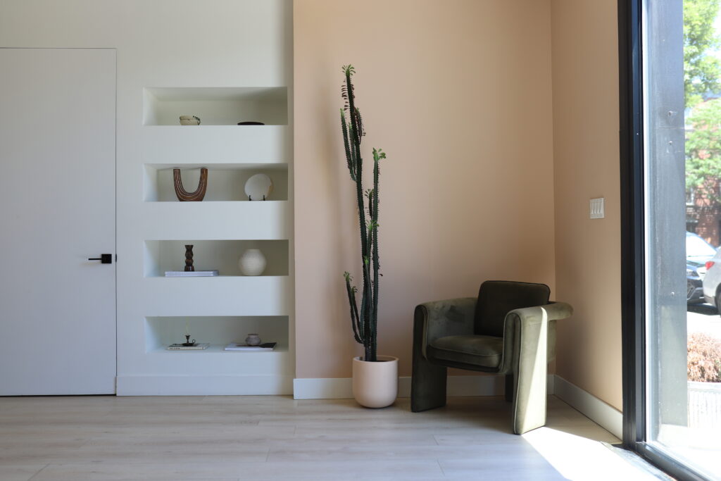 Modern dental office waiting area with minimalist design, built-in shelves, natural light, and calming neutral tones
